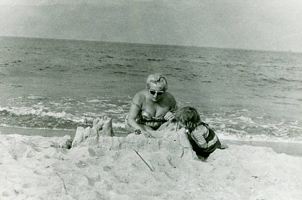 Vintage photo of mother and daughter building sand castle stock photo