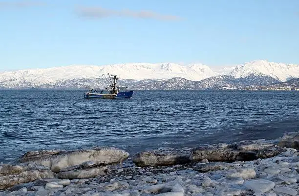 Photo of Blue fishing trawler heading out to sea