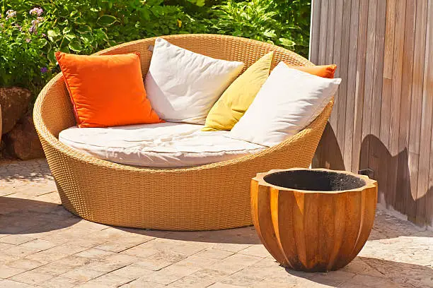 A modern wicker garden sofa or love seat in the home garden.