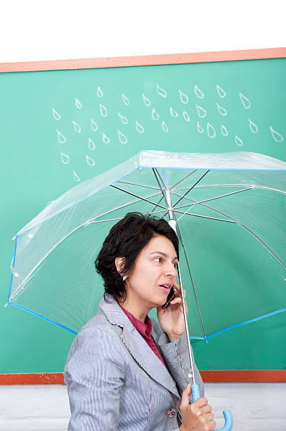 Young woman standing in front of blackboard holding an umbrella stock photo