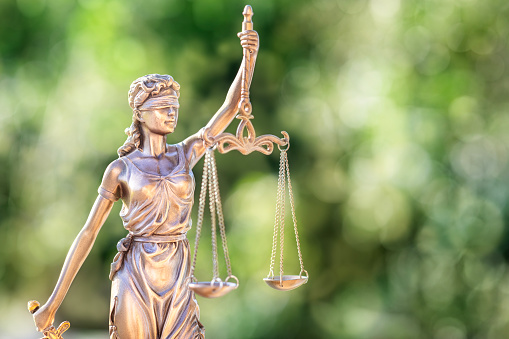 Legal and law concept statue of Lady Justice with scales of justice and green background