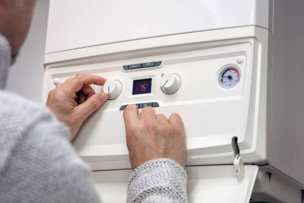 家庭用暖房システムセントラルヒーティングボイラーのサーモスタット設定の調整 - plumber thermostat repairing engineer ストックフォトと画像