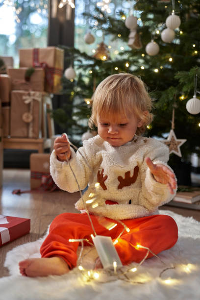 istock Toddler sitting on floor and playing with Christmas lights 1772565980