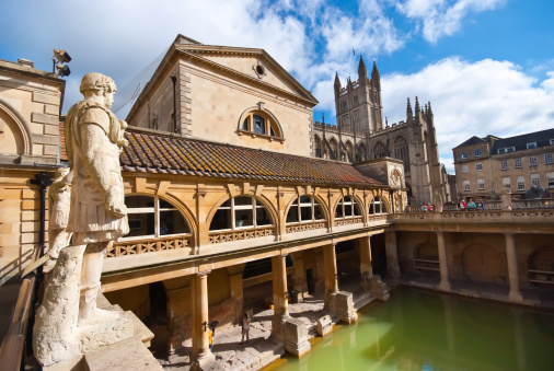 Tourists immerse themselves in history as they visit the iconic Roman Baths inner pool, a captivating glimpse into the ancient past in the charming city of Bath, United Kingdom. A popular landmark, the serene waters mirror the architectural grandeur, inviting visitors to experience the timeless allure of this historical gem