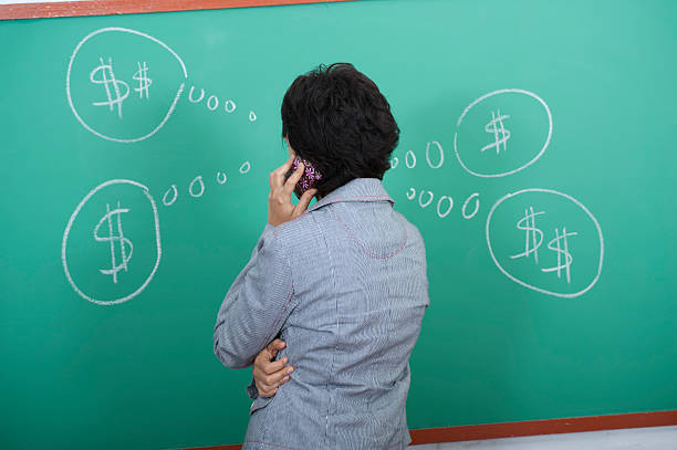 Young woman standing in front of blackboard facing back stock photo