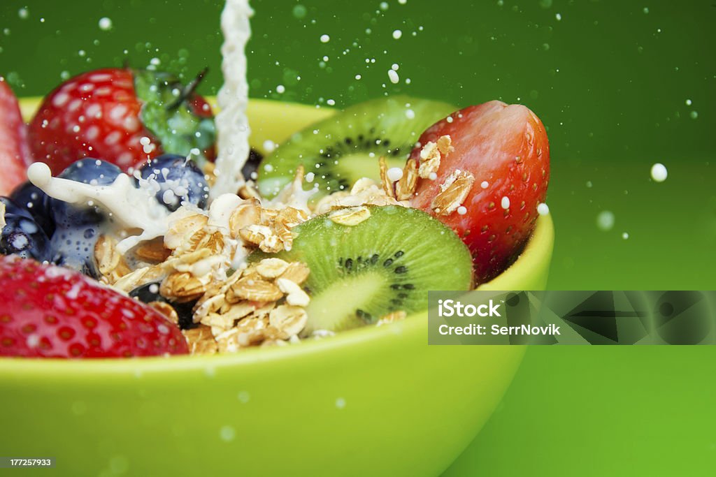 Adding milk to muesli with fruits breakfast Bowl with muesli and fresh berries and fruits with splashing milk Berry Stock Photo