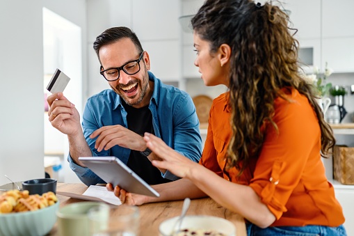 Couple at home paying the bills online using a credit card