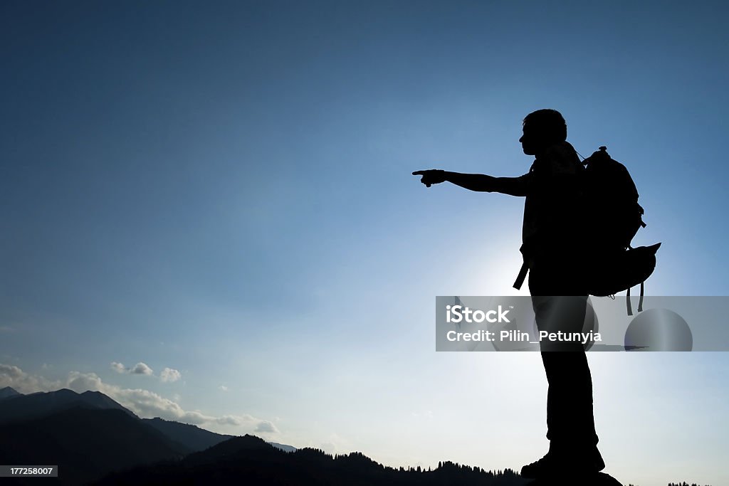 Silhouette of climbing young adult Silhouette of climbing young adult at the top of summit with aerial view of the blue sky Achievement Stock Photo