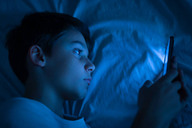 istock Boy using a smartphone at night in bed. 10 year old boy playing with mobile phone before going to sleep. Concept of children using the smartphone in their room alone without control. Copy space 1772580841