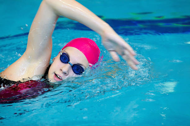 young girl swims freestyle in the pool