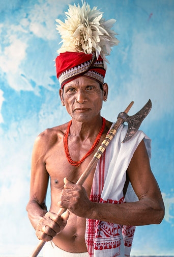 Portrait of a shaman spiritual smile tribal man from the Odisha region of India in a blue background