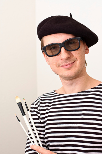 French artist in beret with three brushes