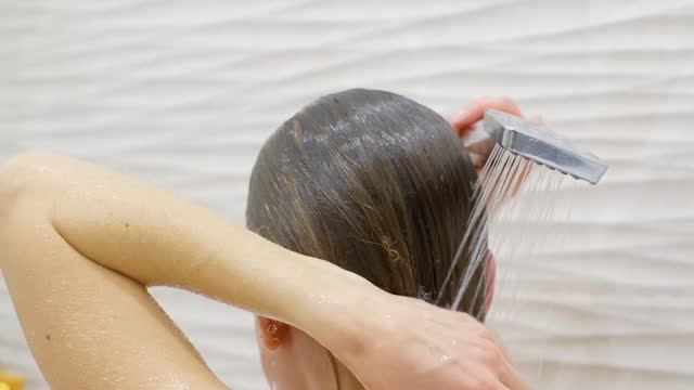 Woman washing her hair with shower, water. Close up.