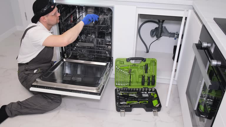 A young male plumber repairs a dishwasher