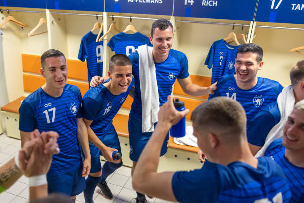 Excited male soccer players winner team celebrating victory, opening sparkling wine in locker room