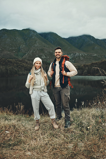 Couple, hiking and portrait in nature with travel, mountain and backpacking with wilderness and explore outdoor. People camping, adventure and holiday with anniversary date, environment and trekking