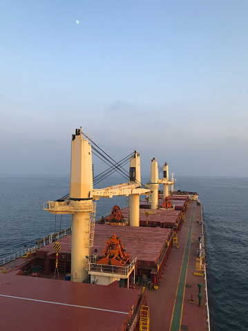 Merchant ship carrying bulk cargo is underway at sea in the morning under low visibility
