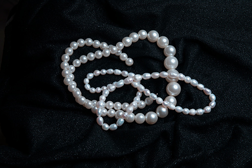 White pearls on a black shiny fabric background