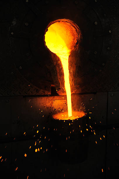 Bright molten metal pouring from ladle into mold stock photo