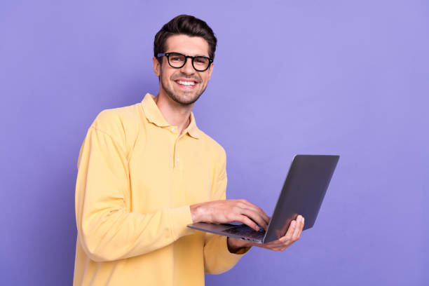 istock Photo of positive charming man dressed yellow shirt texting modern device empty space isolated purple color background 1772637906