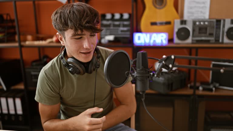 Passionate young hispanic musician, a cheerful teenager wearing headphones, singing his heart out in a music studio with a vibrant smile