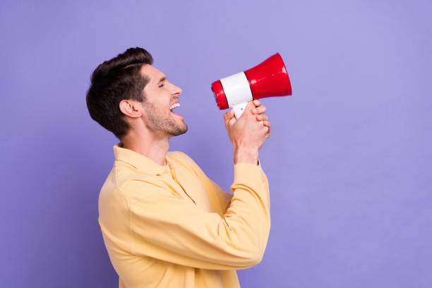 istock Profile portrait of overjoyed positive man hands hold loudspeaker communicate empty space isolated on purple color background 1772642324