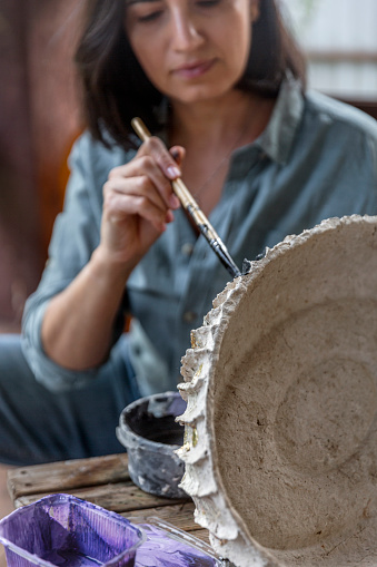 Eco-friendly hobby. Spanish woman painting handmade vase. Recycling
