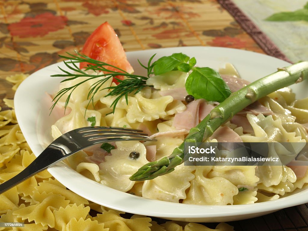 Farfalle with ham salad Farfalle pasta with ham, asparagus, basil and tomato on a plate Appetizer Stock Photo