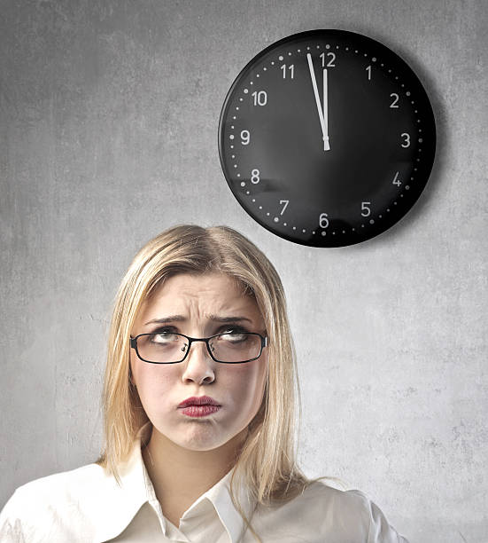 istock Bored blonde woman with glasses underneath a black clock 177265919