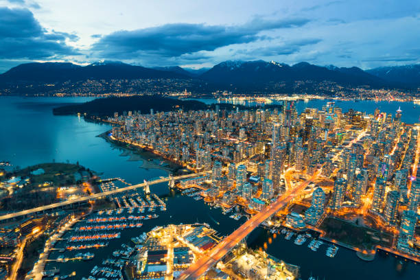 This breathtaking image captures the dynamic essence of Vancouver at night. As darkness descends, the city bursts into a symphony of lights, showcasing a vivid contrast between the urban landscape and the natural beauty of the surrounding mountains and waterways. Iconic structures, bustling streets, and serene harbors are brilliantly illuminated, embodying the vibrant life and architectural elegance of this cosmopolitan city.