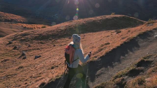 Mature female hiker explores alpine mountainside, autumn