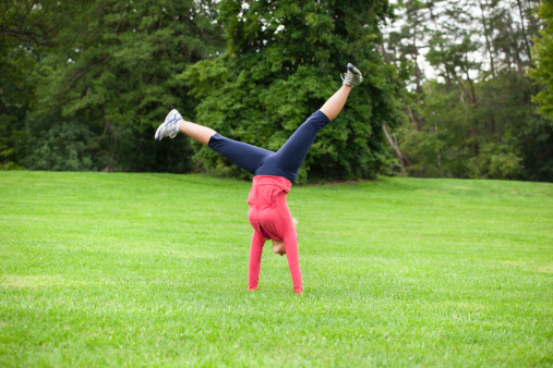 A middle aged woman doing a cartwheel at a park. Motion blur on feet.See more of this