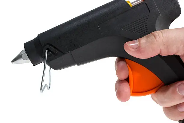 Electric hot glue gun in hand isolated on a white background.