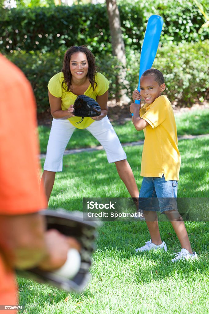 Smiling boy and mother playing baseball with father outdoors African American family, man, woman, boy child, mother, father, son playing baseball together outside. Playing Stock Photo