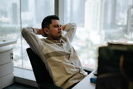 Shot of a young business people frowning while using a laptop in a modern officee