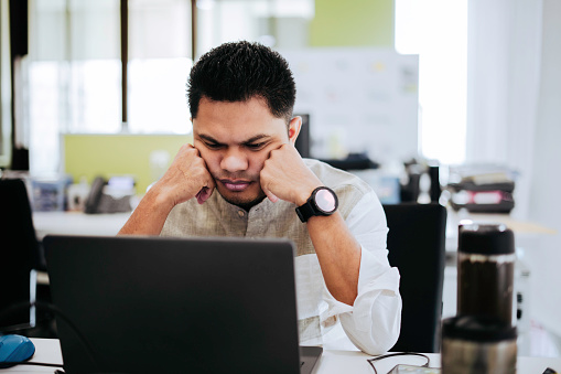 Shot of a young business people frowning while using a laptop in a modern officee