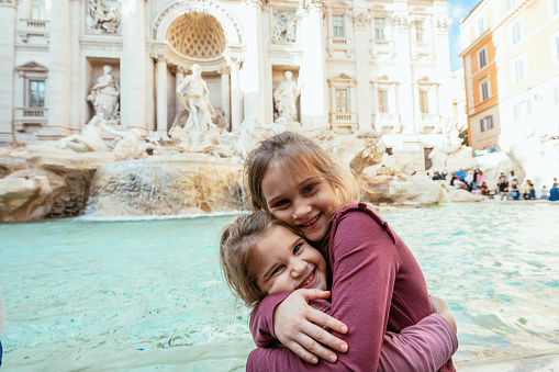 Hand holding colorful gelato in front of famous iconic Trevi Fountain at Rome, Italy.