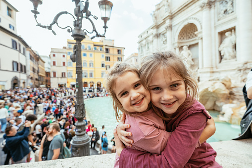 Little girls having a city break with parents and taking tourist photos near landmarks