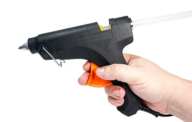 Electric hot glue gun in hand isolated on a white background.