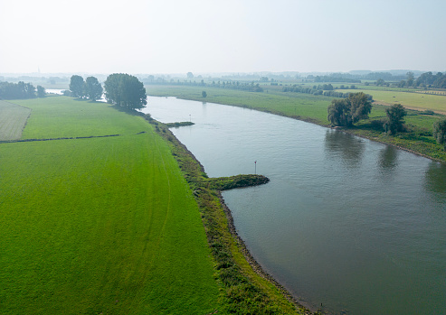 The river IJssel during summer seen from above, early foggy morning.