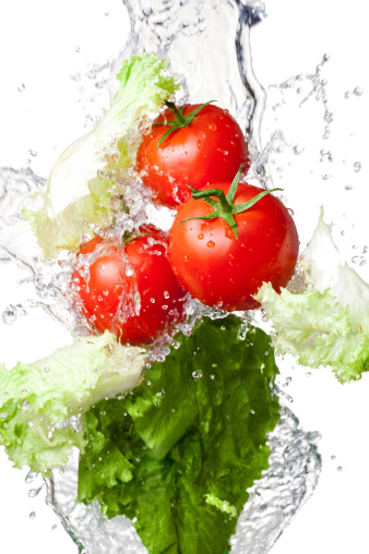 Three Fresh red Tomatoes and lettuce in splash water Isolated on white background