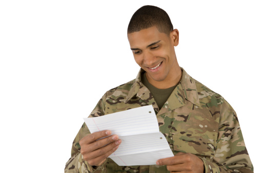 A military man smiles as he reads a letter