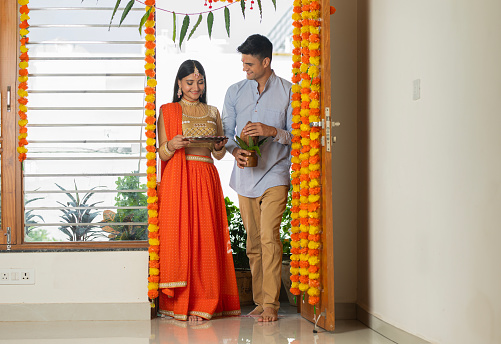 Happy young couple dressed in traditional clothing housewarming at doorway in new house