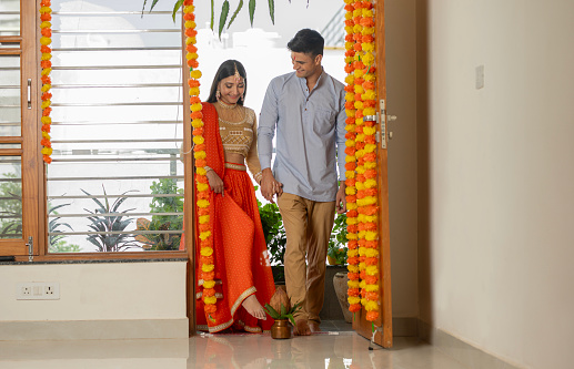 Happy young couple dressed in traditional clothing housewarming at doorway in new house