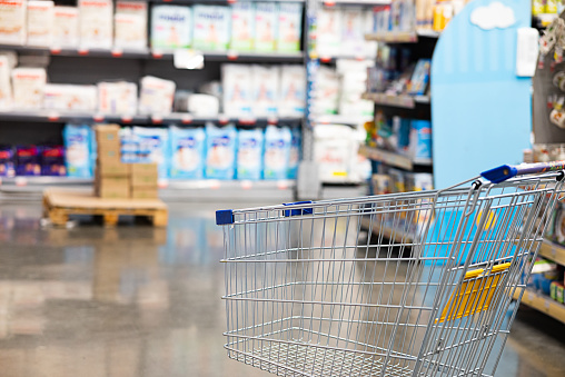 Abstract blurry photo of a supermarket with an empty shopping cart concept.