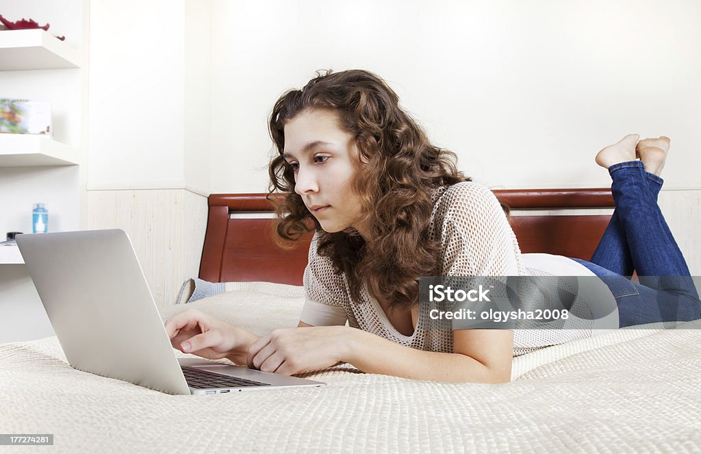 Teenage girl using a computer Looking teenage girl using a computer in her bedroom. Apartment Stock Photo