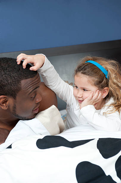 Caucasian girl with afroamerican dad in bed stock photo