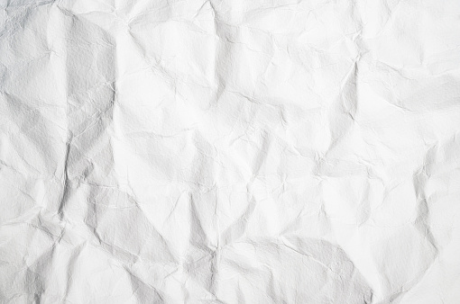 A large surface of white paper, folded and creased to create a background texture.