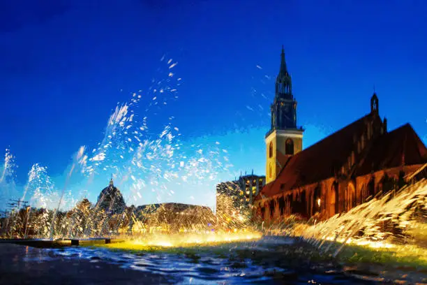 Fantastic view on Church St. Marienkirche  and blue sky of twilights and  blurredfalling in fountains (Wasserkasakaden) in street lights of Berlin. Blurred motion people of long exposure - downtown of German capital