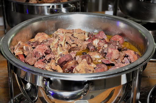 Chafing dish full with potato and beef meat on table